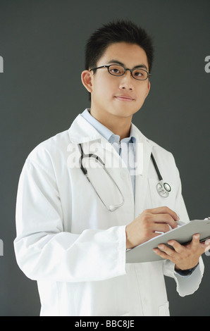 Doctor holding clipboard, looking at camera Banque D'Images