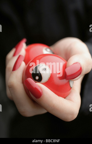 Womans mains avec du vernis à ongles rouge, holding Yin Yang balls, close-up Banque D'Images