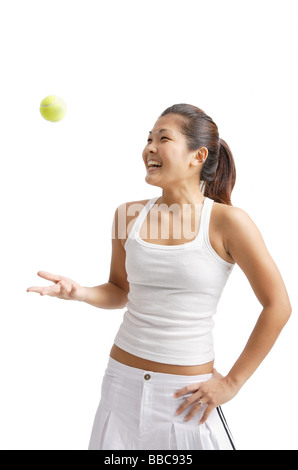 Jeune femme jetant en balle de tennis, hand on hip Banque D'Images