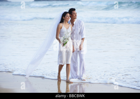Bride and Groom walking on beach Banque D'Images
