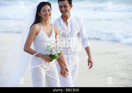 Les nouveaux mariés walking on beach, smiling Banque D'Images