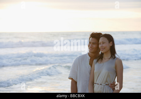 Couple standing on beach, looking away Banque D'Images