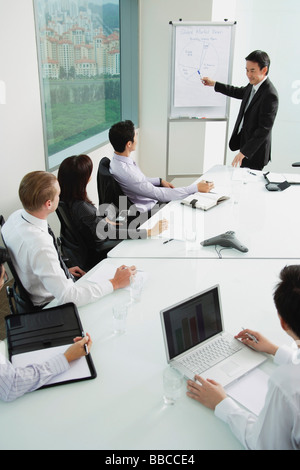 Businessman giving presentation, pointing at whiteboard Banque D'Images