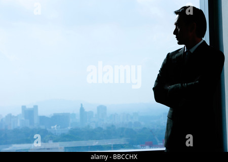 Businessman standing next to baie vitrée Banque D'Images