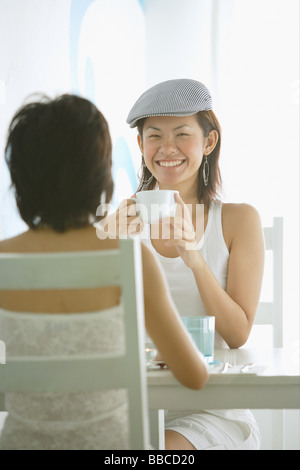 Les jeunes femmes dans un café, assis face à face Banque D'Images
