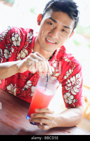Homme portant un t-shirt floral, tenant un verre, looking at camera Banque D'Images