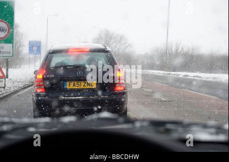 Vue des pilotes à travers un pare-brise de voiture d'attente de circulation sur une route enneigée en Angleterre en hiver Banque D'Images