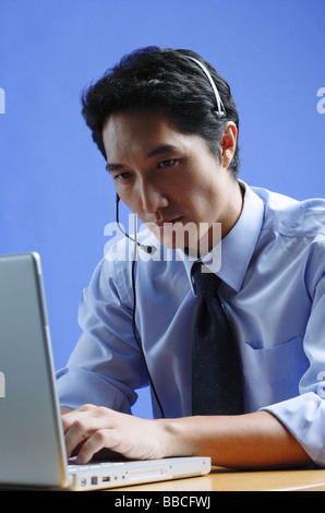 Homme portant un casque, using laptop Banque D'Images