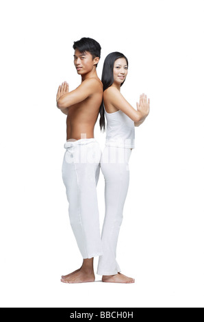 Couple doing yoga, debout dos à dos, looking at camera Banque D'Images