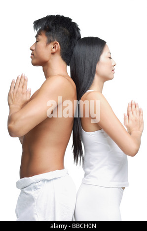 Couple debout dos à dos en position de yoga, side view Banque D'Images