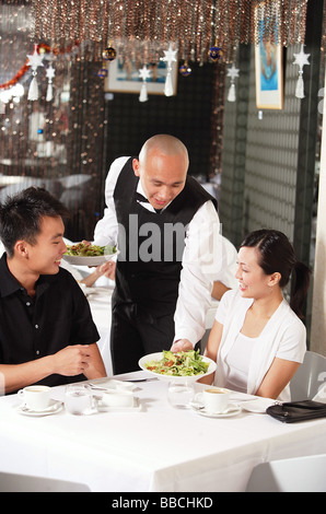 Waiter serving couple at restaurant Banque D'Images
