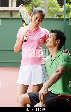 Couple en tenue de tennis, smiling at each other Banque D'Images