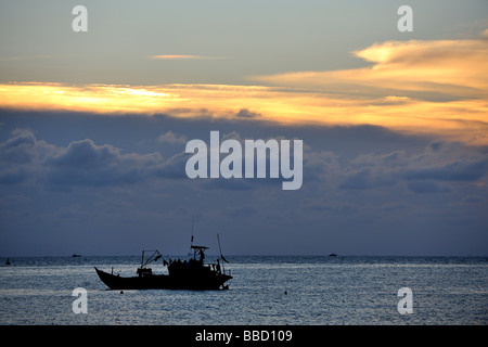 Bateau de pêche silhouetté contre le soleil couchant. Hang Dua Bay, Bai Truoc (Front Beach ou Tam Duong), Vung Tau, Vietnam Banque D'Images