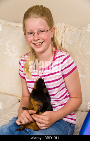 Laughing Young Caucasian 10-11 ans, fille, tenant son cobaye MR © Myrleen Pearson Banque D'Images