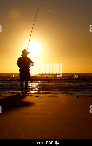 Pêcheur sur la plage au lever du soleil Banque D'Images