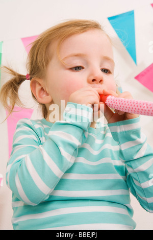 Petite fille soufflant une crécelle at a Birthday Party Banque D'Images