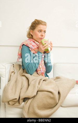 Woman holding Mug Sitting on Sofa Banque D'Images