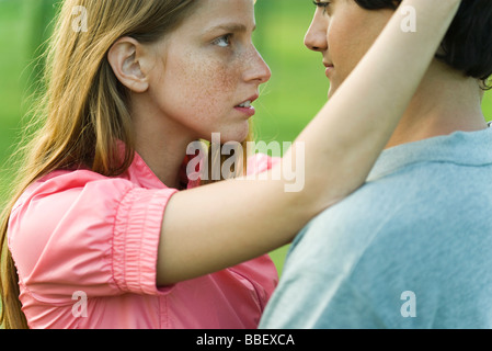Jeune couple regardant fixement dans les yeux, side view Banque D'Images
