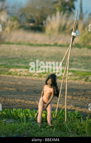 Jeu de poupée contre trellis in vegetable garden Banque D'Images