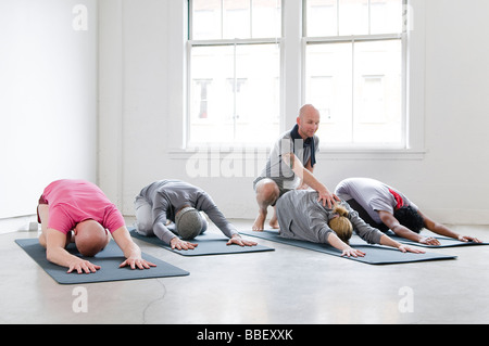 Les élèves s'étirer avec l'aide de l'instructeur de yoga, Vancouver, Colombie-Britannique Banque D'Images