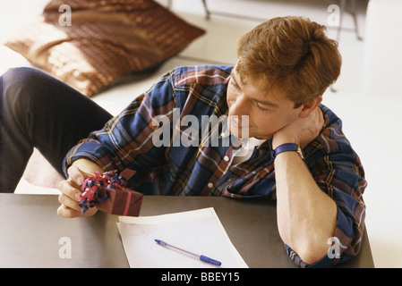 Man holding gift, note sur la table basse en face de lui Banque D'Images