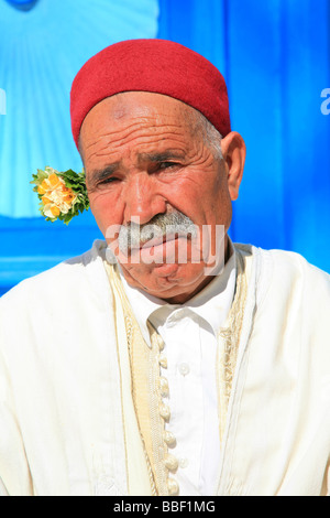 Vieil Homme avec moustache en costume traditionnel avec un fez rouge et de jasmin dans les cheveux Banque D'Images