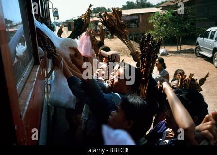 Les vendeurs de rue offrent des collations locales aux passagers d'un bus en provenance de Paxxe à Savannakhet au Laos. Banque D'Images