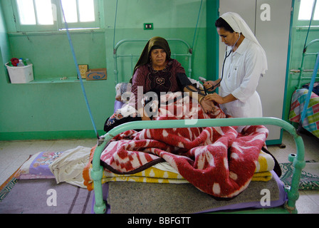 Soeur Laura est chekcing le pouls d'une des personnes âgées malades de la lèpre dans la léproserie de l'Égypte. Banque D'Images