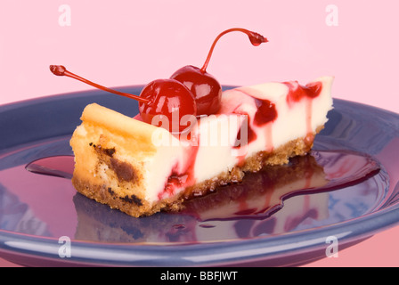 Une tranche de gâteau au fromage aux cerises cerises fraîches avec la sauce aux cerises et un fond rose Banque D'Images