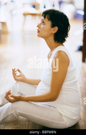 Pregnant woman meditating on marbre, vue latérale Banque D'Images