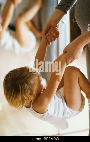 Little girl holding mother's hands, tournant flip contre son ventre Banque D'Images