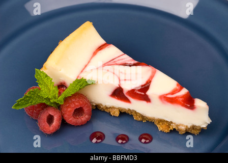 Une tranche de gâteau au fromage aux framboises dessert avec des feuilles de menthe dans une assiette de service Banque D'Images