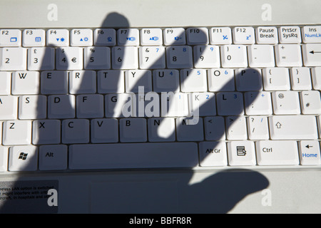 Ombre de main sur clavier d'ordinateur. Banque D'Images