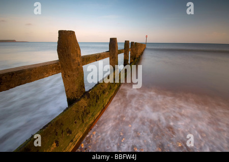 Se précipiter à travers les vagues de la mer en bois sur la défense britannique Devon Dawlish Warren beach Banque D'Images