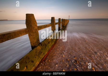 Se précipiter à travers les vagues de la mer en bois sur la défense britannique Devon Dawlish Warren beach Banque D'Images