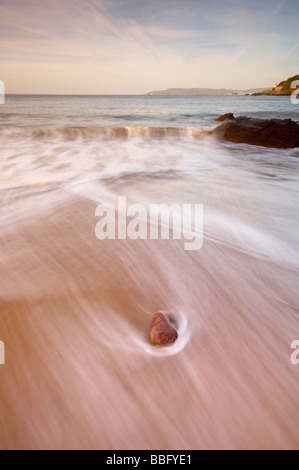 Se précipitant dans les vagues sur la plage à Bovisand bay à l'aube Devon UK Banque D'Images