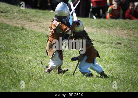 Les enfants jouent lutte avec des épées au cours de la promulgation d'une bataille médiévale au Château Ogrodzieniec, Pologne. Banque D'Images