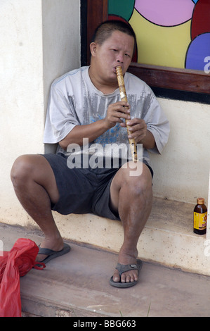 Garçon laotien la lecture d'une flûte en bois à Vientiane, Laos Banque D'Images