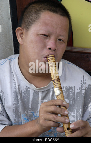 Garçon laotien la lecture d'une flûte en bois à Vientiane, Laos Banque D'Images