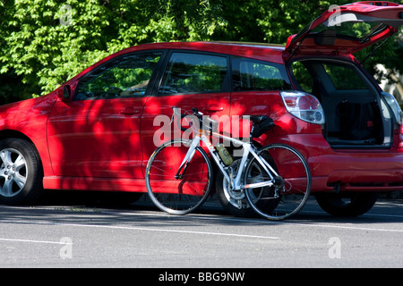 Un vélo de route en appui sur une voiture avec le capot écoutille est ouverte. Banque D'Images