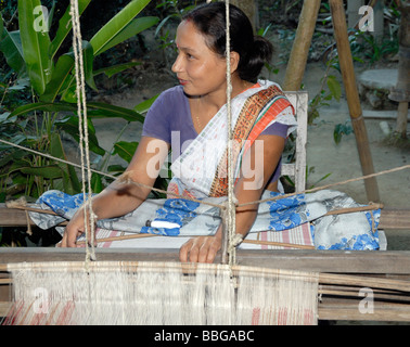 Une femme qui a mis en place une coopérative de tisserandes de soie démontre le processus de tissage sur un métier à la maison. Banque D'Images