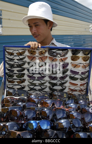 Garçon cambodgien de vendre de fausses lunettes de soleil dans les rues du centre de Phnom Penh, Cambodge Banque D'Images