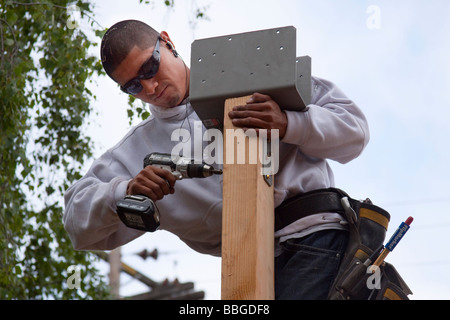 Carpenter en utilisant un effet conducteur de fixer un support pour un post avec des boulons Banque D'Images