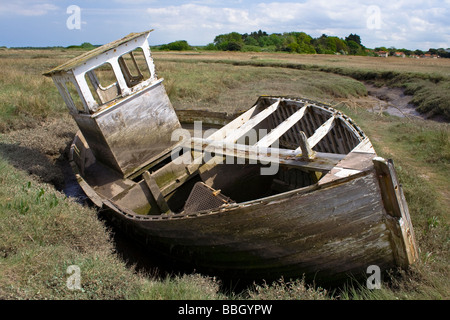 L'épave d'un bateau de pêche se trouvant dans la boue sur les marais, sur la côte nord de Norfolk Banque D'Images