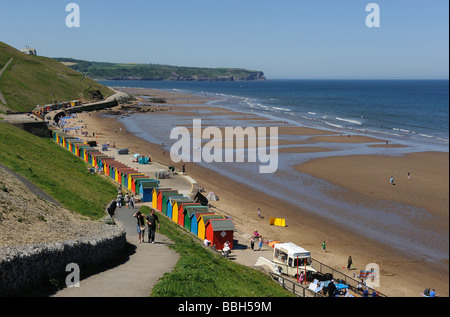 La fabuleuse plage à Whitby sur une magnifique journée d'été. Les cabanes de plage prêter un peu de couleur à la scène. Banque D'Images