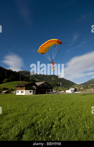 Parachutiste est volant sous canoy et va atterrir sur une belle pelouse de la paix. Le parachute stable dans le ciel bleu. Banque D'Images
