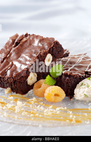 Brownie au chocolat servi avec des framboises et de la crème glacée jaune Banque D'Images