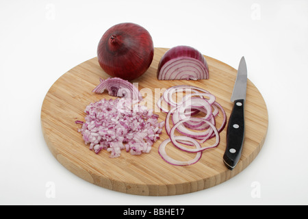 Oignons rouges (Allium cepa), pelées, coupées en dés les oignons, les rondelles d'oignon sur une planche en bois, avec un couteau Banque D'Images