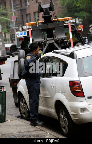 Remorquer le chariot avec NYPD police femmes essayant d'avoir accès à la voiture à l'aide d'un long morceau de fil épais Manhattan NEW YORK USA Banque D'Images