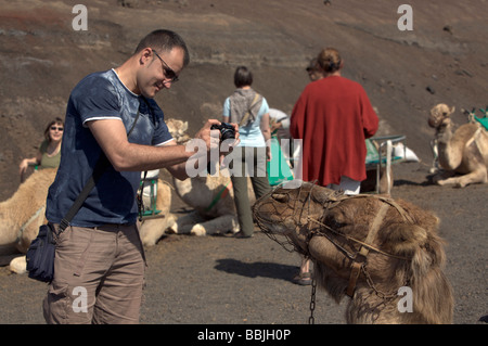 Les touristes et vacanciers profiter un dromadaire chameau dans le Parc National de Timanfaya, Lanzarote. Banque D'Images